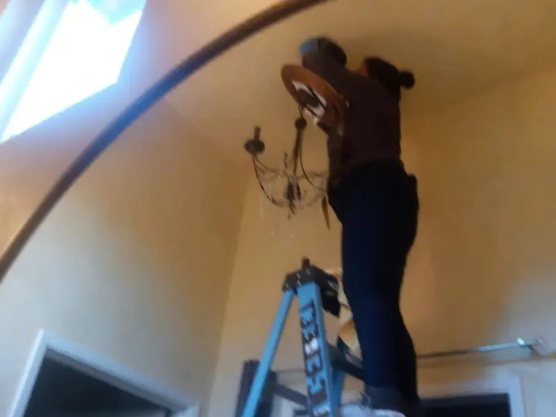 Electrician installing a chandelier in a Marseilles residence